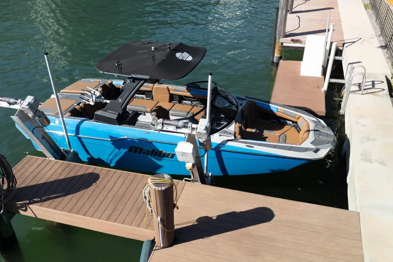 Slide: The Image of 2020 Malibu M240 boat docked, featuring sleek design and blue exterior. - 20