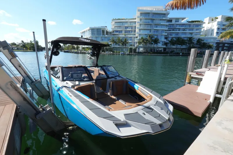 Slide: The Image of 2020 Malibu M240 boat docked by waterfront luxury apartments. - 21