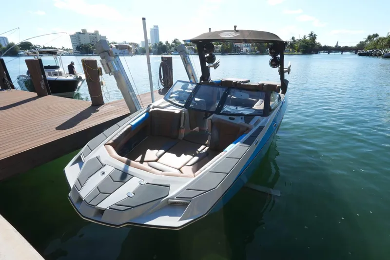 Slide: The Image of 2020 Malibu M240 boat docked on a sunny waterfront with modern design. - 22