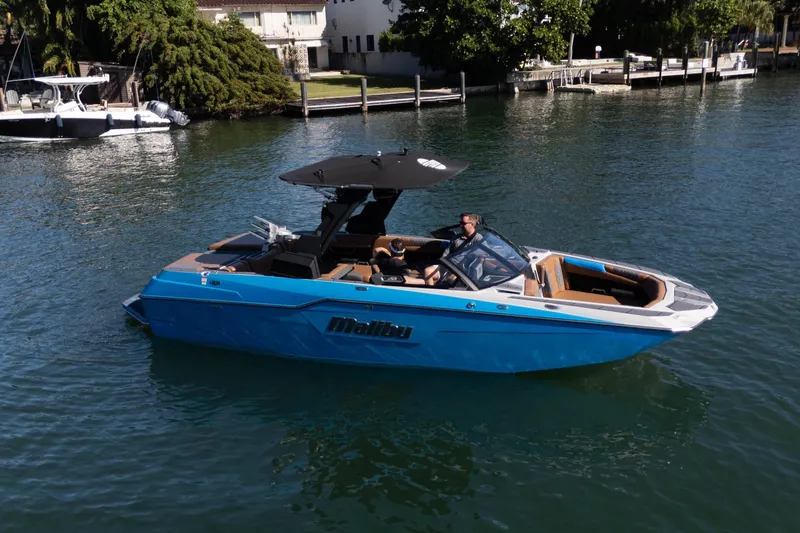Slide: The Image of 2020 Malibu M240 boat cruising on a serene waterway. - 3