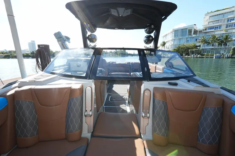 Slide: The Image of Interior view of a 2020 Malibu M240 boat with luxurious seating and waterfront backdrop. - 30