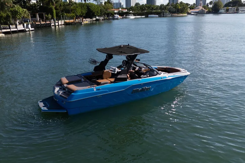 Slide: The Image of 2020 Malibu M240 boat cruising on a calm, scenic waterway. - 5