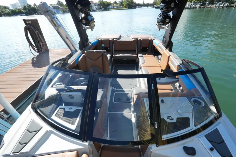 Slide: The Image of 2020 Malibu M240 boat interior with brown seating, docked by the water. - 7