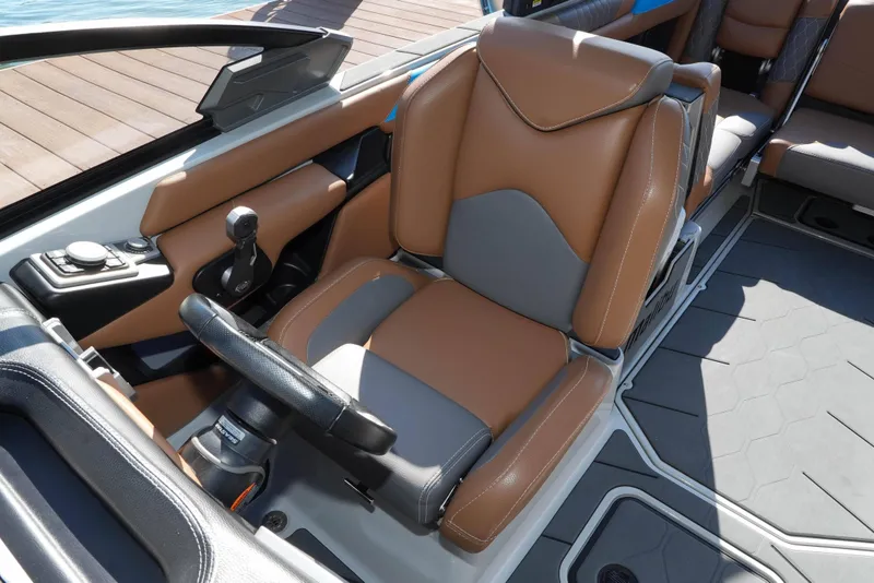 Slide: The Image of 2020 Malibu M240 boat interior with tan and gray seating, steering wheel, and controls. - 9