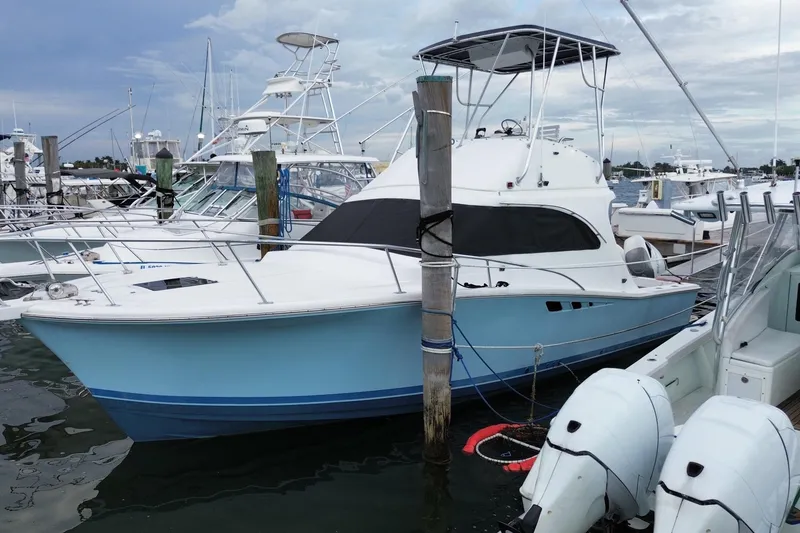 The Image of 1994 Luhrs 32 Convertible boat docked at marina, featuring a sleek blue and white design. - 0