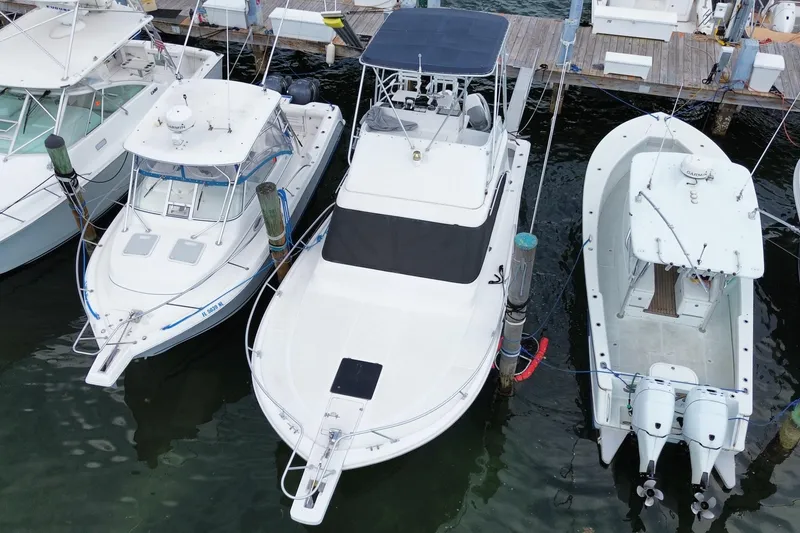 Slide: The Image of 1994 Luhrs 32 Convertible boat docked between two other boats at a marina. - 10