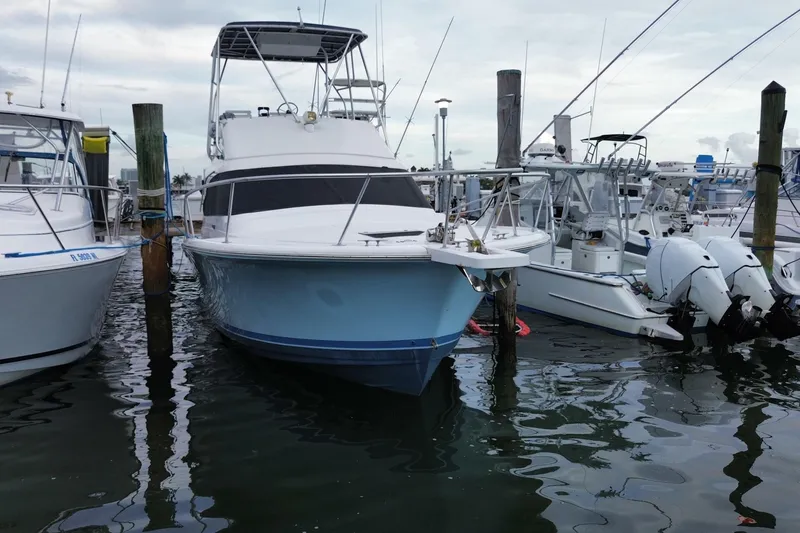 Slide: The Image of 1994 Luhrs 32 Convertible boat docked at marina, surrounded by other vessels. - 12