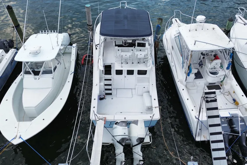 Slide: The Image of 1994 Luhrs 32 Convertible boat docked between two other boats in a marina. - 14