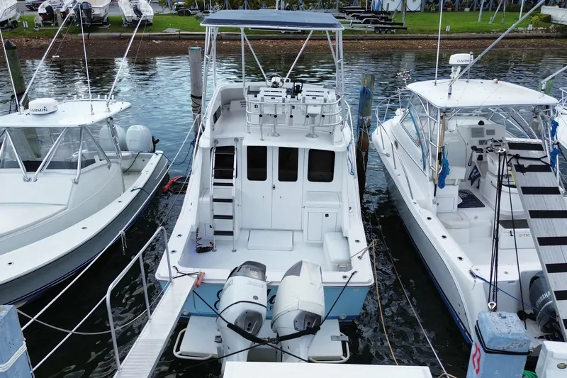 Slide: The Image of 1994 Luhrs 32 Convertible boat docked between two other vessels in a marina. - 15
