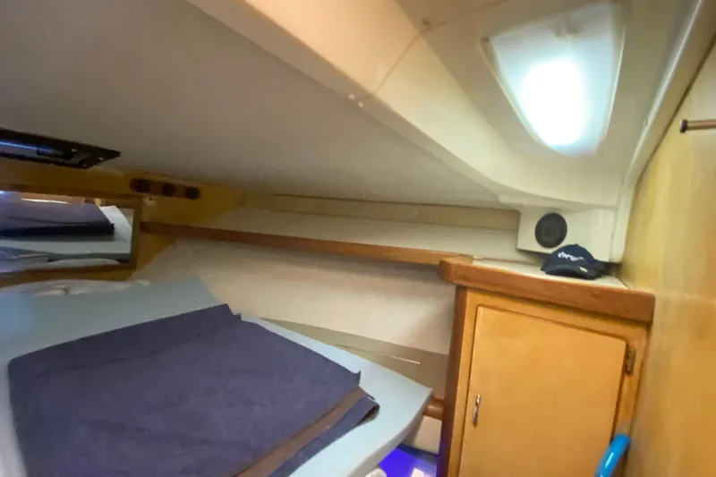Slide: The Image of 1994 Luhrs 32 Convertible cabin interior with bed, storage, and natural light. - 38