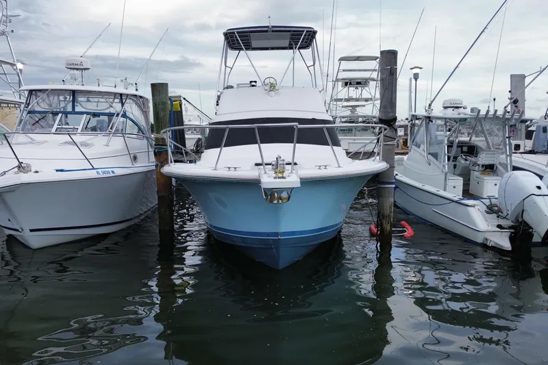 Slide: The Image of 1994 Luhrs 32 Convertible boat docked between two other vessels at a marina. - 6