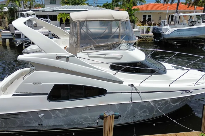 The Image of 2002 Silverton 330 Sport Bridge yacht docked at marina, featuring sleek design and spacious deck. - 0