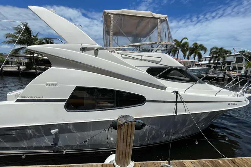 Slide: The Image of 2002 Silverton 330 Sport Bridge yacht docked, featuring sleek design and spacious cabin. - 14