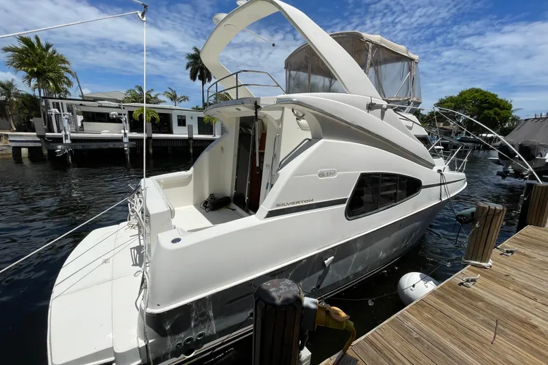 Slide: The Image of 2002 Silverton 330 Sport Bridge yacht docked by waterfront homes under blue sky. - 15