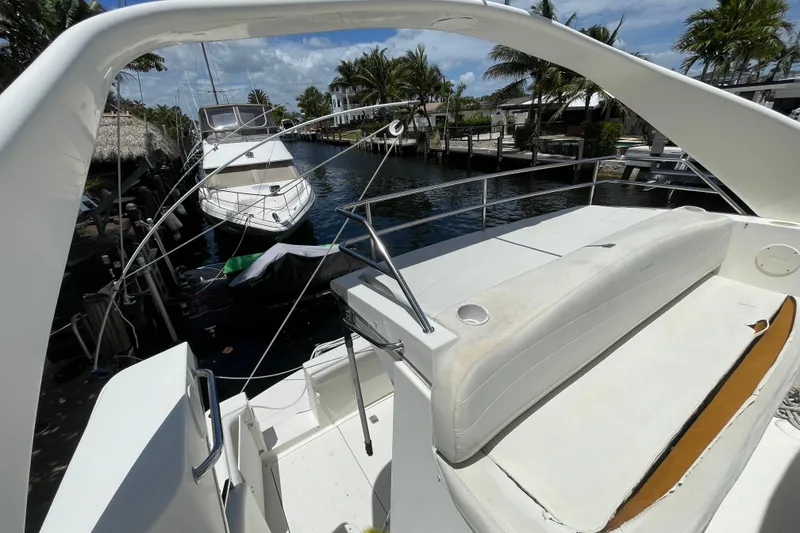Slide: The Image of 2002 Silverton 330 Sport Bridge yacht docked by palm trees and waterfront homes. - 20