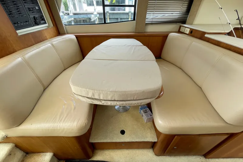 Slide: The Image of Interior of 2002 Silverton 330 Sport Bridge with beige seating and table. - 24