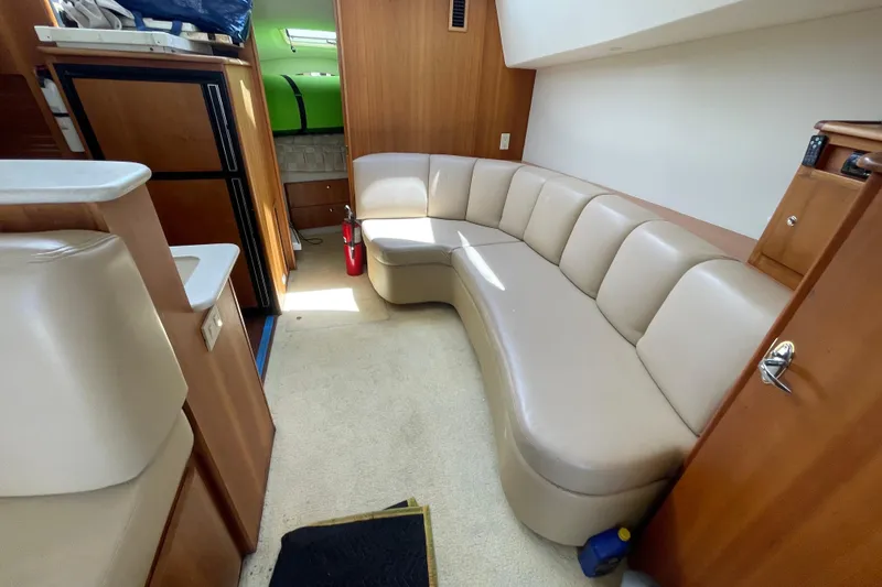 Slide: The Image of 2002 Silverton 330 Sport Bridge interior with curved beige seating and wooden cabinetry. - 29