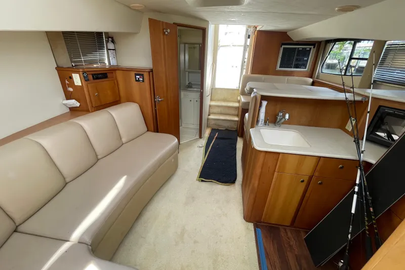 Slide: The Image of Interior of a 2002 Silverton 330 Sport Bridge yacht with beige seating and wooden cabinetry. - 34