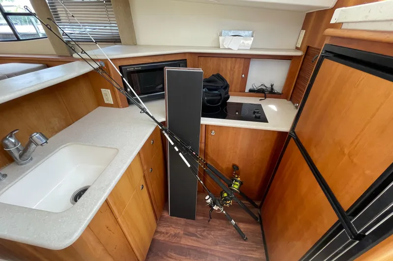 Slide: The Image of Interior of 2002 Silverton 330 Sport Bridge with fishing rods and kitchenette. - 36
