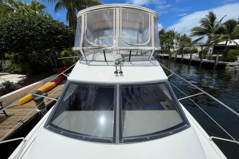 Slide: The Image of 2002 Silverton 330 Sport Bridge yacht docked by tropical waterfront. - 4