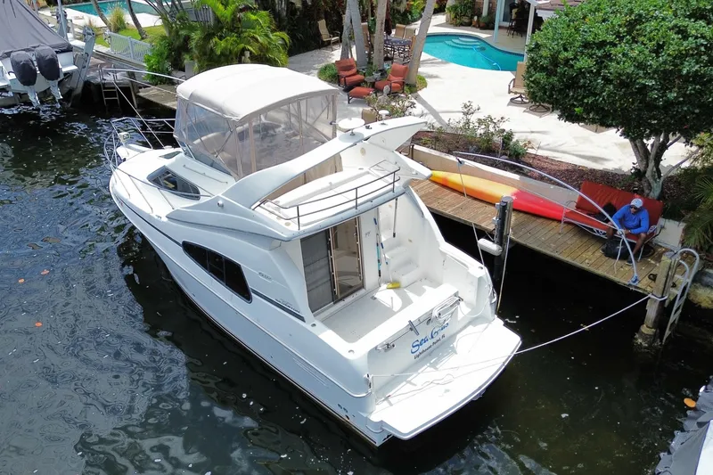Slide: The Image of 2002 Silverton 330 Sport Bridge yacht docked near a poolside patio. - 44