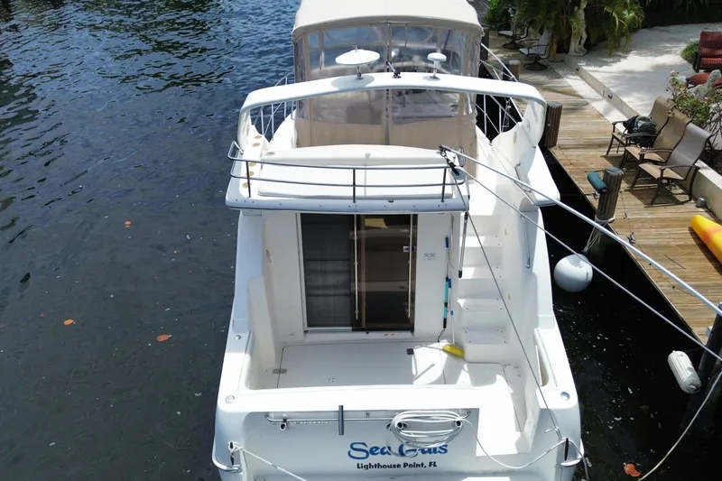 Slide: The Image of 2002 Silverton 330 Sport Bridge docked, rear view, with spacious deck and canopy. - 49