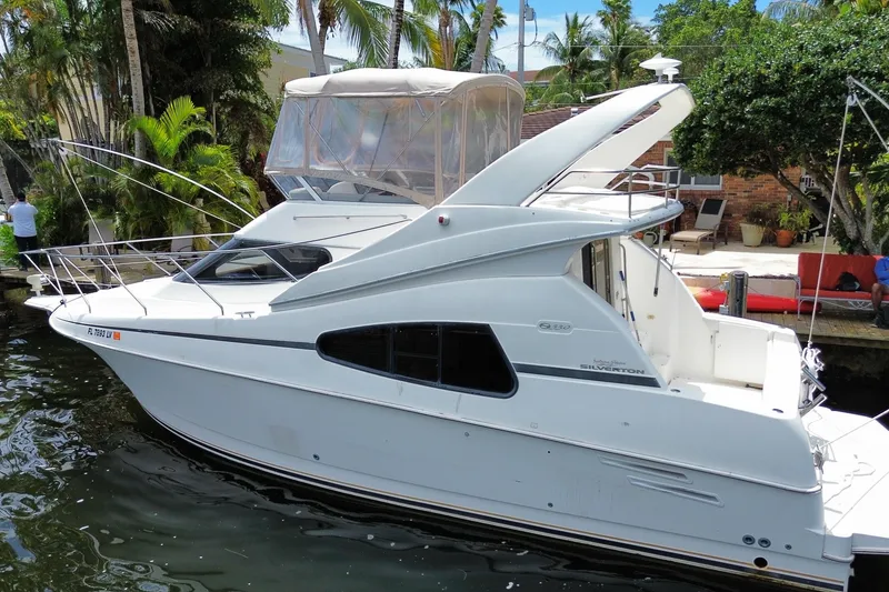 Slide: The Image of 2002 Silverton 330 Sport Bridge yacht docked by lush greenery. - 55
