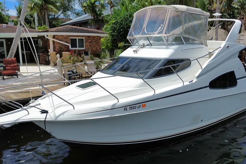 Slide: The Image of 2002 Silverton 330 Sport Bridge yacht docked near a waterfront home. - 58