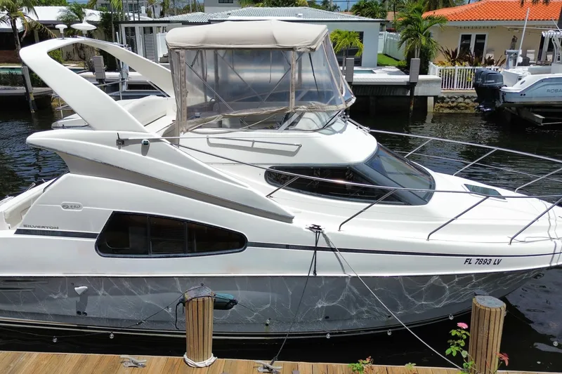 Slide: The Image of 2002 Silverton 330 Sport Bridge yacht docked at a marina, featuring sleek design and spacious cabin. - 59