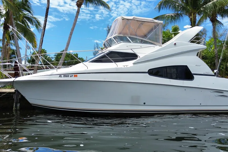 Slide: The Image of 2002 Silverton 330 Sport Bridge yacht docked by palm trees under blue sky. - 61