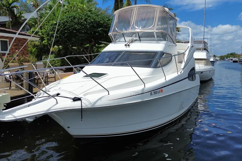 Slide: The Image of 2002 Silverton 330 Sport Bridge yacht docked by a canal, surrounded by lush greenery. - 64