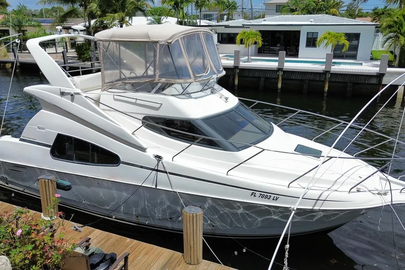 Slide: The Image of 2002 Silverton 330 Sport Bridge yacht docked by waterfront home. - 69