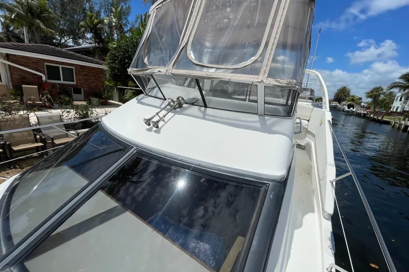 Slide: The Image of 2002 Silverton 330 Sport Bridge yacht docked by a canal under a clear blue sky. - 8