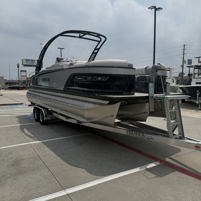 Slide: The Image of 2026 Avalon QLS25T Excalibur pontoon boat on trailer outdoors. - 6