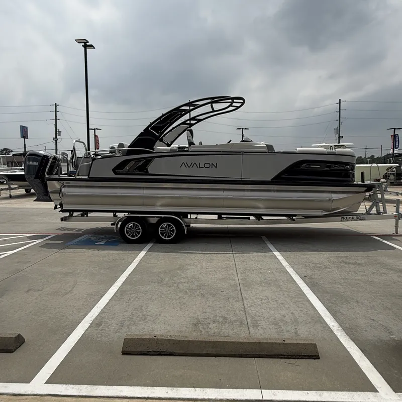 Slide: The Image of 2026 Avalon QLS25T Excalibur pontoon boat on trailer outdoors. - 7