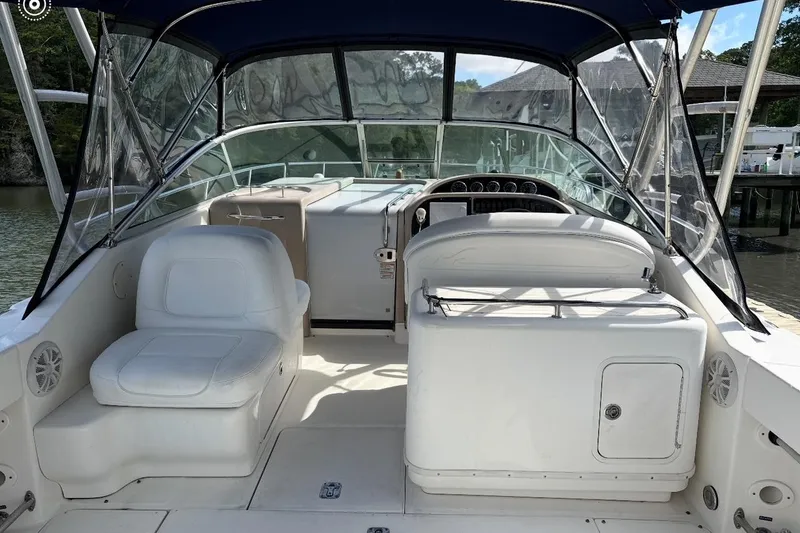 Slide: The Image of 2005 Sea Ray 290 Amberjack boat interior with seating and dashboard, docked by the water. - 6