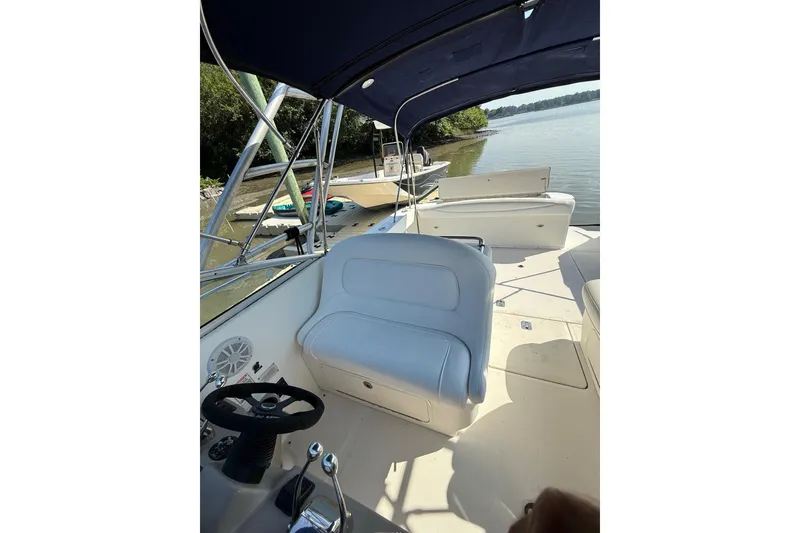 Slide: The Image of 2005 Sea Ray 290 Amberjack boat interior with helm and seating, docked by a calm lake. - 9