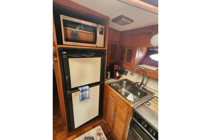Slide: The Image of 1988 Marine Trader 43 galley with microwave, fridge, sink, and stove in wooden cabinetry. - 19