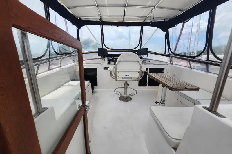 Slide: The Image of 1988 Marine Trader 43 cockpit with helm, seating, and wooden table under canopy. - 35