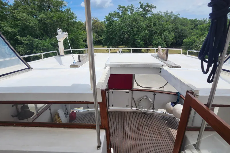 Slide: The Image of 1988 Marine Trader 43 yacht deck with wooden flooring and railing, surrounded by lush greenery. - 38