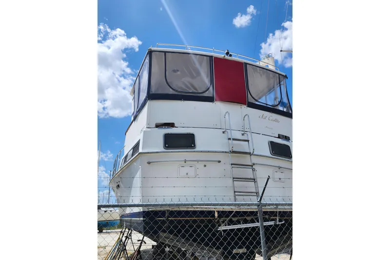 Slide: The Image of 1988 Marine Trader 43 yacht on land, blue sky background, fenced area. - 45