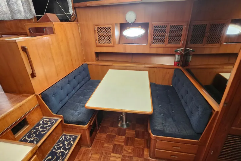 Slide: The Image of 1988 Marine Trader 43 interior with wooden dining area and blue cushioned seating. - 8