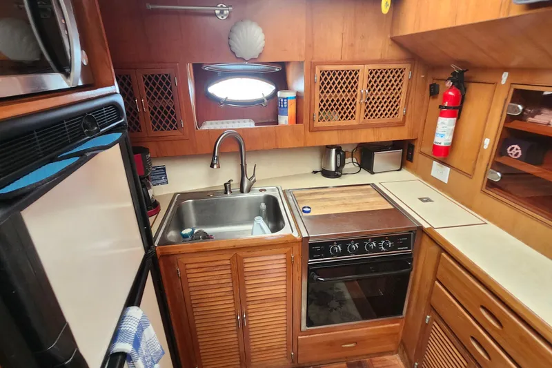 Slide: The Image of 1988 Marine Trader 43 yacht kitchen with wooden cabinets, sink, stove, and fire extinguisher. - 9