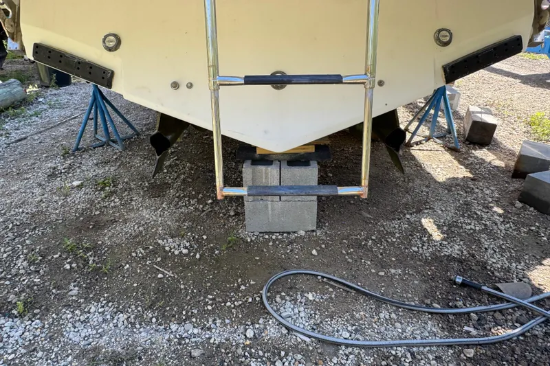 Slide: The Image of 2006 Formula 40 Performance Cruiser on blocks, ladder attached, gravel ground. - 28