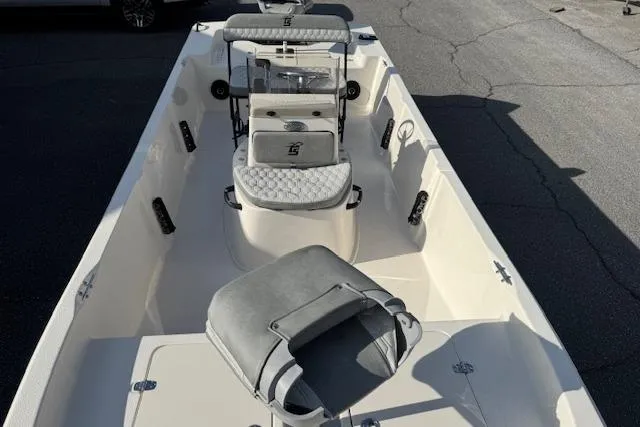 Slide: The Image of 2026 Carolina Skiff 192 JLS boat interior with seating and console, parked on pavement. - 6