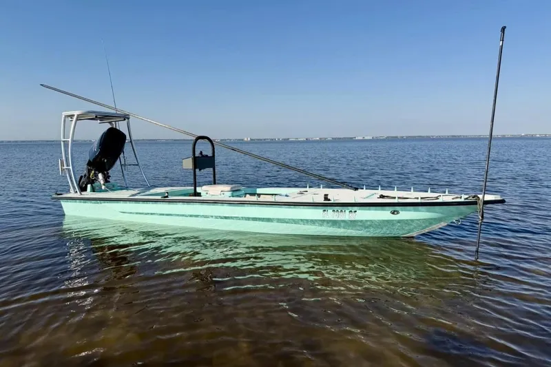 The Image of 2017 Cayo Boatworks 173 skiff on calm water, featuring a sleek design and outboard motor. - 1