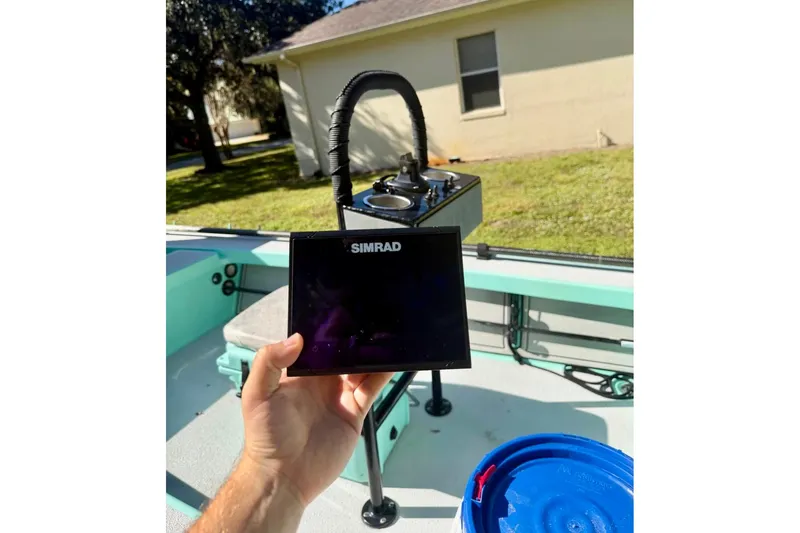 Slide: The Image of Hand holding Simrad device on 2017 Cayo Boatworks 173, with outdoor background. - 8