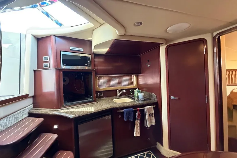 Slide: The Image of 2007 Sea Ray 380 Sundancer yacht interior with kitchenette, featuring microwave, sink, and wooden cabinetry. - 20