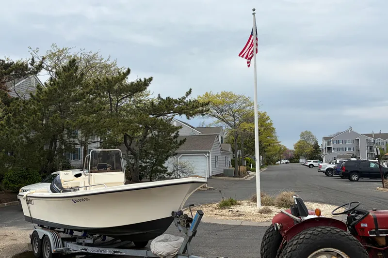 Slide: The Image of 2003 Parker 21SE Center Console boat on trailer near residential street with American flag. - 2