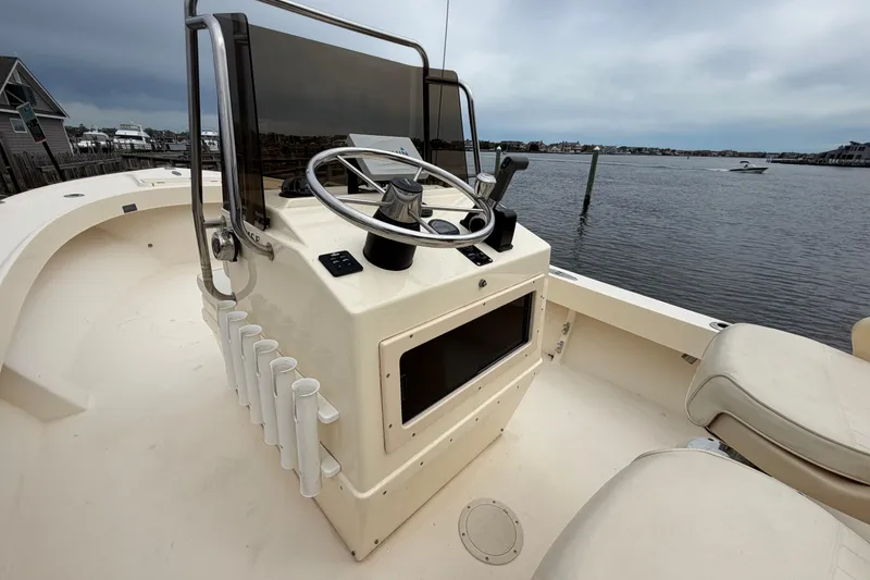 Slide: The Image of 2003 Parker 21SE Center Console boat with steering wheel, rod holders, and waterfront view. - 29